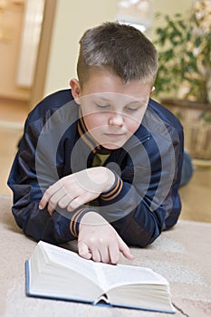 Boy reading book on carpet