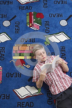Boy Reading Book On Floor