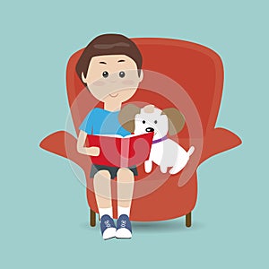 Boy reading the book on the sofa with his dog