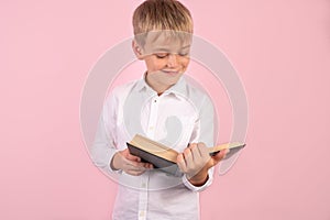 Boy reading a book thirsty for knowledge - isolated over pink background