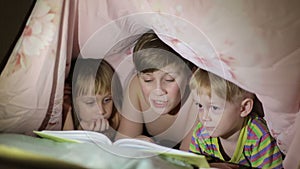 Boy reading a book to his brother and sister