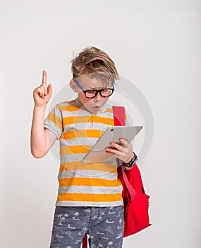 Boy reading an e-book instead of books. Caucasian 7 years old boy with tablet computer pointing up with a finger