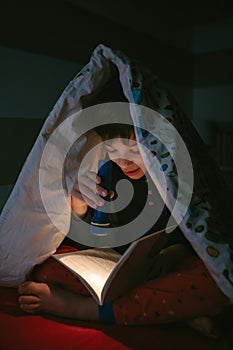 Boy reading with a flashlight