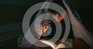 Boy reading with a flashlight