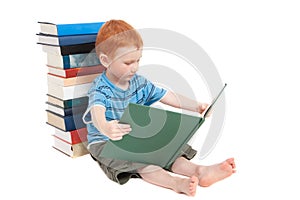 Boy reading kids book and leaning on stacked books