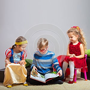 Boy reads a book to little girls