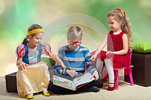 Boy reads a book to little girls