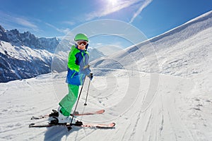 Boy ready to ski on snow slope over mountain peaks