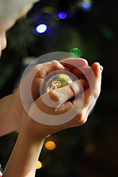 A boy in a red cap holds a Christmas toy in his hands with his reflection