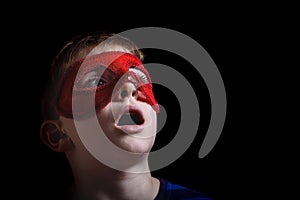 Boy in red carnival mask on black background. Portrait closeup isolated