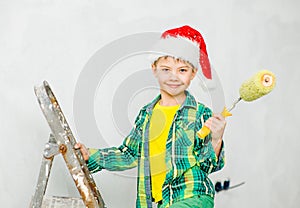 boy in a red christmas hat holding roller for painting