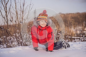 Boy in red fashion clothes playing outdoors. Active leisure with children in winter on cold days. Boy having fun with