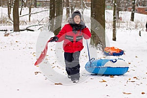 A boy in a red jacket down on a sled with a snow slide