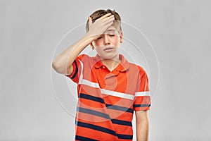 Boy in red polo t-shirt having headache