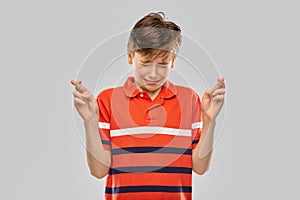 Boy in red polo t-shirt holding fingers crossed