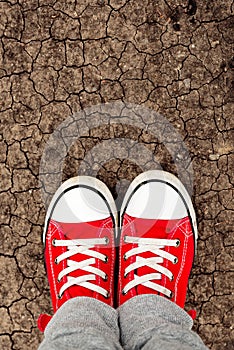 Boy in red sneakers standing on the ground, from above