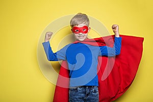 Boy in red super hero cape and mask. Superman. Studio portrait over yellow background