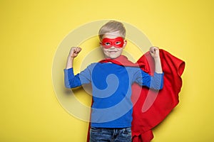 Boy in red super hero cape and mask. Superman. Studio portrait over yellow background