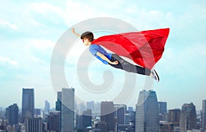 Boy in red superhero cape and mask flying on air