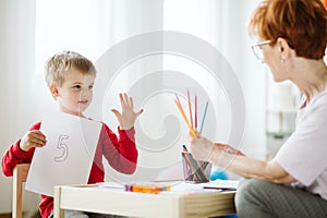 Boy in red sweater learning to count during extra-curricular activities photo