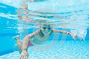 Boy in red swim trunks under water