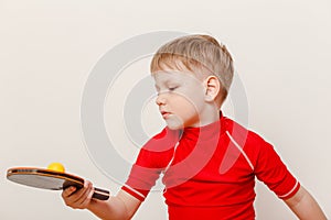Boy in red t-shirt holding table tennis racket and ball