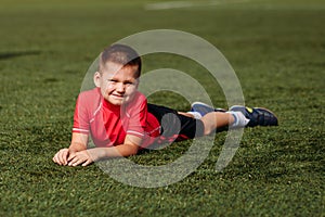 Boy in red T-shirt lies on green grass