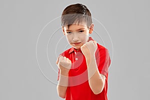 Boy in red t-shirt showing fists or boxing