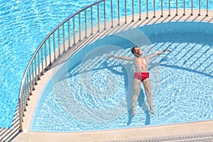 The boy in the red trunks floating in the pool