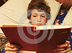 Boy reeding book in bed close up photo