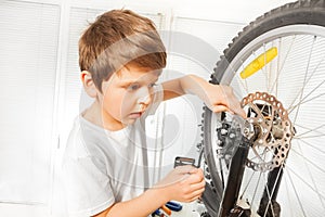 Boy repairing bike drawing up a bolt with spanner