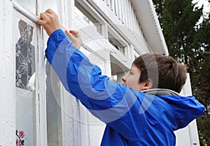 Boy repairing window on the outside.