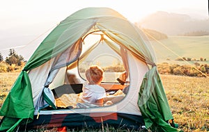 Boy rest in camping tent and enjoy with sunset light in mountain valley