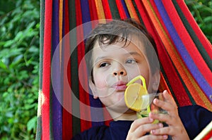 boy resting in a hammock in nature, drinking a cocktail with lemon. teenager Relaxing In Hammock. vacation concept