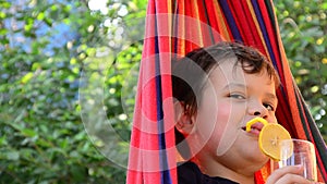 boy resting in a hammock in nature, drinking a cocktail with lemon. teenager Relaxing In Hammock. vacation concept