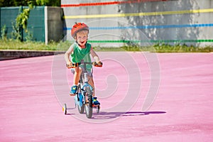 Boy ride small bicycle with learning wheels on color surface