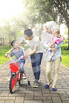Boy rides bicycle with family at park