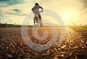 Boy rides a bicycle in the sunset light