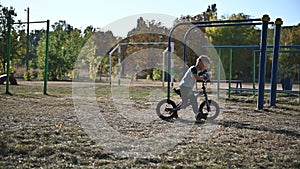 The boy rides on a runbike in the park in summer sunny weather having a good mood