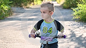 The boy rides on a runbike in the park in summer sunny weather having a good mood