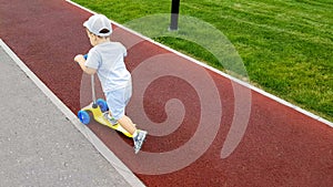 Boy rides a scooter along the tracks