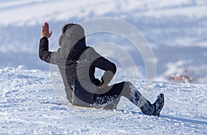 The boy rides a sled from the mountain in winter