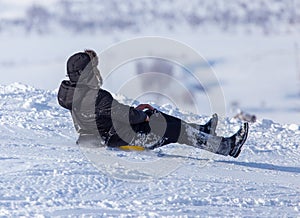 The boy rides a sled from the mountain in winter