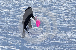 The boy rides a sled from the mountain in winter