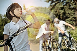 Boy riding bicycle and drinking water