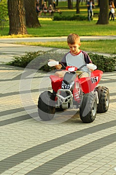 Boy riding big red toy car in park