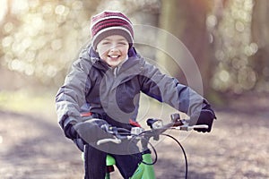 Boy riding his bicycle and laughing in autumn leaves in the park