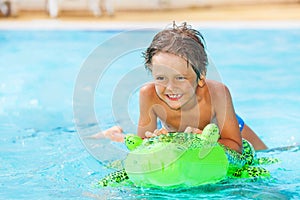 Boy riding inflatable toy in swimming pool