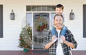 Boy Riding Piggyback on Shoulders of Father On Christmas Decorated Front Porch