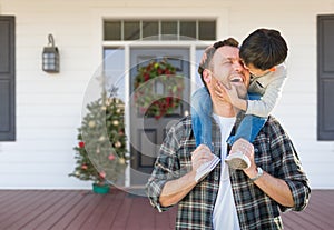 Boy Riding Piggyback on Shoulders of Father On Christmas Decorated Front Porch